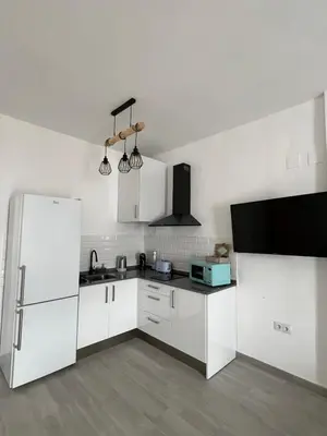 a kitchen with white cabinets and a refrigerator at Apartamentos Turísticos Antonio Parra in Jerez de la Frontera