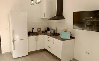 a kitchen with white cabinets and a refrigerator at Apartamentos Turísticos Antonio Parra in Jerez de la Frontera