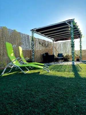 a green chair sitting in the grass in a backyard at Casa Rural El Pequeño Oasis in Arcos de la Frontera