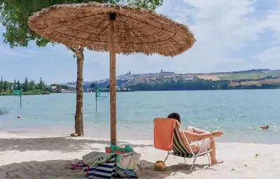 a person sitting in a chair under an umbrella on the beach at Casa Rural El Pequeño Oasis in Arcos de la Frontera