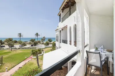 a balcony with a table and chairs and the ocean at Pinomar, estupendo apartamento en primera línea de playa in Chiclana de la Frontera