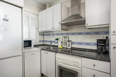 a kitchen with white cabinets and a sink at Pinomar, estupendo apartamento en primera línea de playa in Chiclana de la Frontera