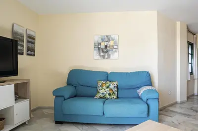 a blue couch with a pillow in a living room at Pinomar, estupendo apartamento en primera línea de playa in Chiclana de la Frontera