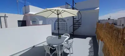 a white table and chairs on a balcony with an umbrella at Ático en Chipiona in Chipiona