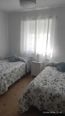 a bedroom with two beds and a dresser with a lamp at Ático en Chipiona in Chipiona