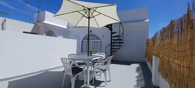 a patio with a table and chairs and an umbrella at Ático en Chipiona in Chipiona