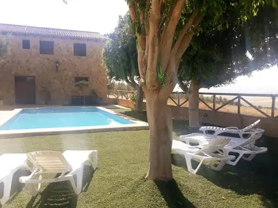 a pool with two lounge chairs and a tree at Casa Rural El Almendrillo in Arcos de la Frontera