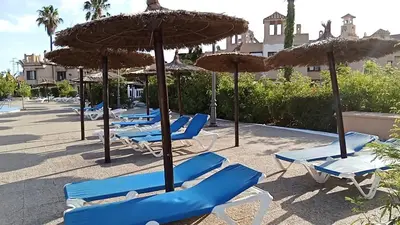 a row of blue lounge chairs and umbrellas at Apartamentos Jasmund - Bungalow 87 in San Fernando