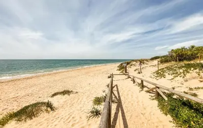 a sandy beach with a wooden fence next to the ocean at 2 Bedroom Stunning Apartment In Rota in Rota