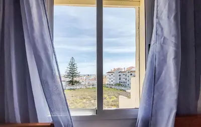a window with blue curtains and a view of a city at 2 Bedroom Stunning Apartment In Rota in Rota