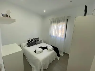 a white bedroom with a bed with black and white pillows at Chalet Benamejí in Sanlúcar de Barrameda