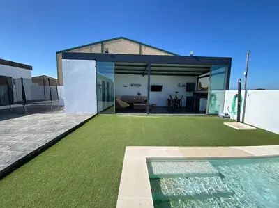 a house with a green yard with a swimming pool at Chalet Benamejí in Sanlúcar de Barrameda