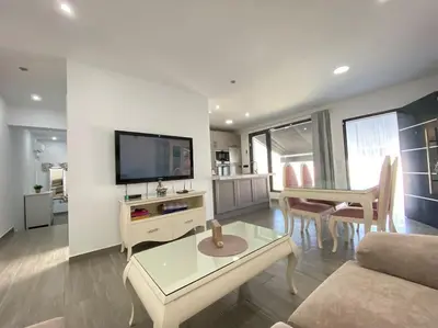 a living room with a couch and a tv and a table at Chalet Benamejí in Sanlúcar de Barrameda