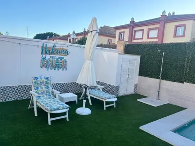 a patio with two chairs and an umbrella next to a pool at Soto de Vistahermosa in El Puerto de Santa María