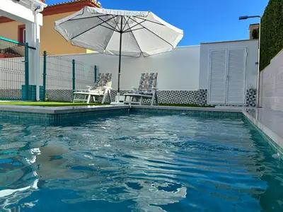 a swimming pool with an umbrella and a table and chairs at Soto de Vistahermosa in El Puerto de Santa María