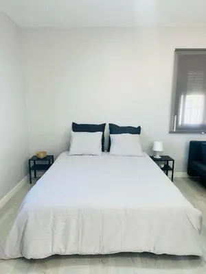 a white bed with white sheets and pillows at Alojamiento Carlota in Chiclana de la Frontera