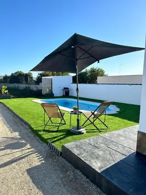 two chairs and an umbrella next to a pool at Alojamiento Carlota in Chiclana de la Frontera