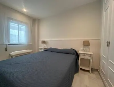 a bedroom with a blue bed and a window at Apartoyou - Vistahermosa Lux in El Puerto de Santa María