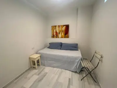 a small bedroom with a bed and a chair at Apartoyou - Vistahermosa Lux in El Puerto de Santa María