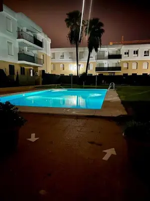 a swimming pool in front of a building at night at La Bodega del Mar - Luminoso y céntrico apto con piscina en verano y parking in El Puerto de Santa María