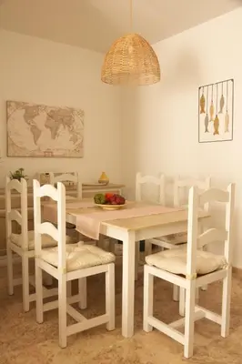 a dining room with a table and white chairs at La Bodega del Mar - Luminoso y céntrico apto con piscina en verano y parking in El Puerto de Santa María