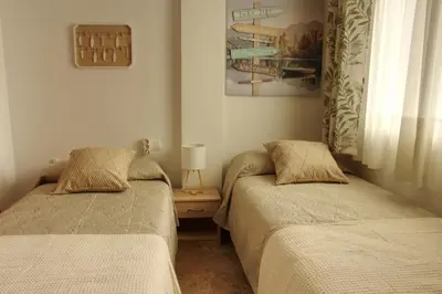 a bedroom with two beds and a table with a lamp at La Bodega del Mar - Luminoso y céntrico apto con piscina en verano y parking in El Puerto de Santa María