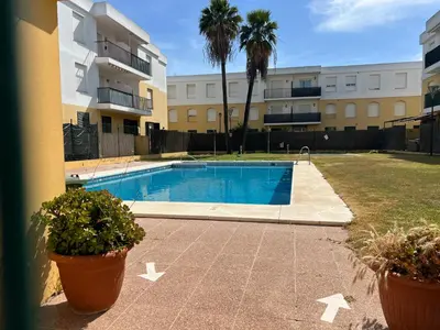 a swimming pool with two potted plants next to a building at La Bodega del Mar - Luminoso y céntrico apto con piscina en verano y parking in El Puerto de Santa María
