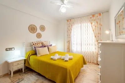 a bedroom with a yellow bed with towels on it at Apartamento playa Victoria in Cádiz
