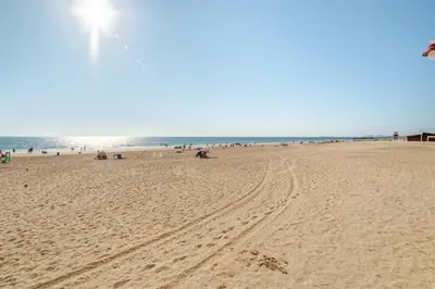 a beach with people sitting on the sand and the ocean at Apartamento playa Victoria in Cádiz