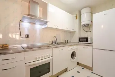 a white kitchen with a sink and a dishwasher at Apartamento playa Victoria in Cádiz