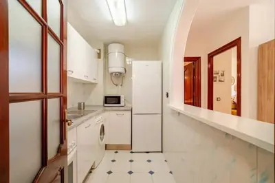 a kitchen with a white refrigerator and a tile floor at Apartamento playa Victoria in Cádiz
