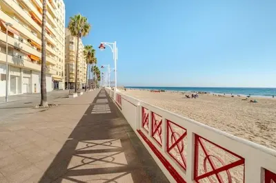 a sandy beach with buildings and the ocean at Apartamento playa Victoria in Cádiz