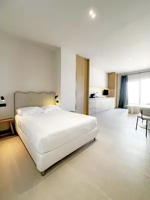a bedroom with a large white bed and a kitchen at CASA MONTI Sherry Suites in Jerez de la Frontera