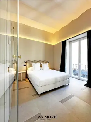 a bedroom with a white bed and a glass shower at CASA MONTI Sherry Suites in Jerez de la Frontera