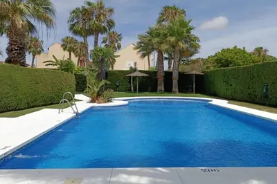 a swimming pool in a yard with palm trees at Apto en El Puerto de Santa María in El Puerto de Santa María