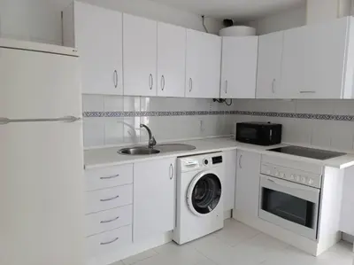 a white kitchen with a washing machine and a sink at Apto en El Puerto de Santa María in El Puerto de Santa María