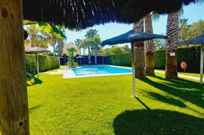 a yard with an umbrella and a swimming pool at Apto en El Puerto de Santa María in El Puerto de Santa María