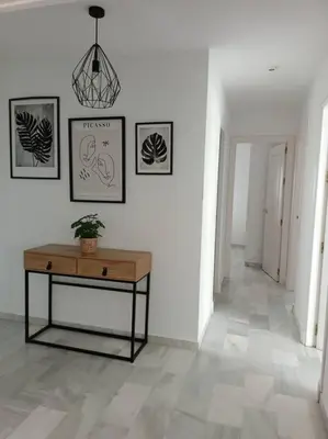 a hallway with a table and pictures on the wall at Apto en El Puerto de Santa María in El Puerto de Santa María