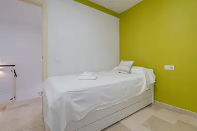 a bedroom with a white bed with green walls at Apartoyou - Breva Playa in El Puerto de Santa María