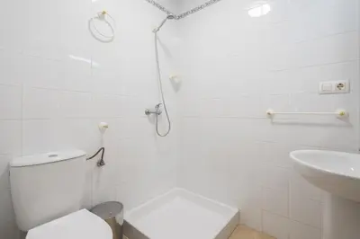 a white bathroom with a toilet and a sink at Apartoyou - Breva Playa in El Puerto de Santa María