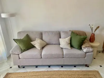 a gray couch with green pillows in a living room at ÁTICO Centro y Playa in Sanlúcar de Barrameda