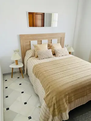 a bedroom with a large bed and a mirror at ÁTICO Centro y Playa in Sanlúcar de Barrameda