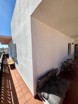 a balcony with a couch against a white wall at ÁTICO Centro y Playa in Sanlúcar de Barrameda