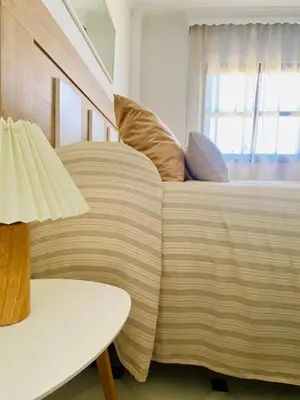 a bedroom with a bed with pillows and a table at ÁTICO Centro y Playa in Sanlúcar de Barrameda
