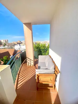 a balcony with a bed and a view of the ocean at ÁTICO Centro y Playa in Sanlúcar de Barrameda