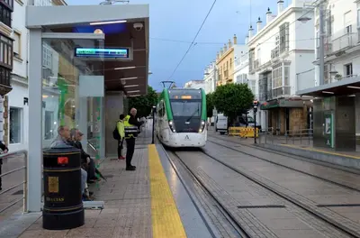 a green and white train pulling into a train station at La Isla Centro in San Fernando