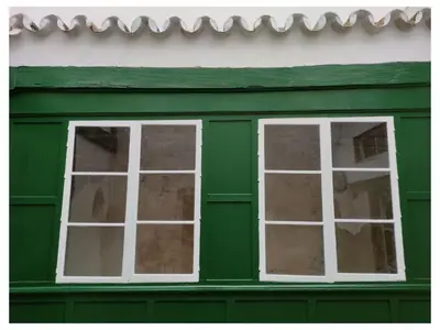 two windows on the side of a green building at LA BARAKA APARTAMENTO in Jerez de la Frontera