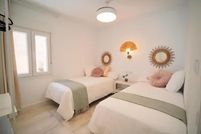 a bedroom with two beds and a mirror at Sibs Sanlúcar Atlantico Playa Vistas Reformado in Sanlúcar de Barrameda