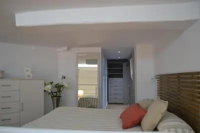 a white bedroom with a bed and a dresser at Apartamento en Playa Victoria in Cádiz