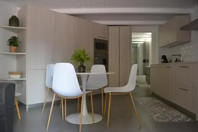 a kitchen with white chairs and a table at Apartamento en Playa Victoria in Cádiz
